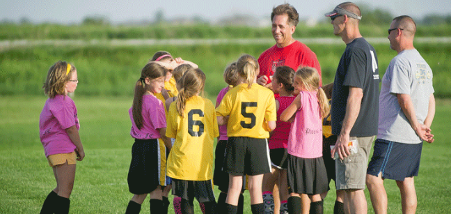 A group of girls and coaches on a soccer field
